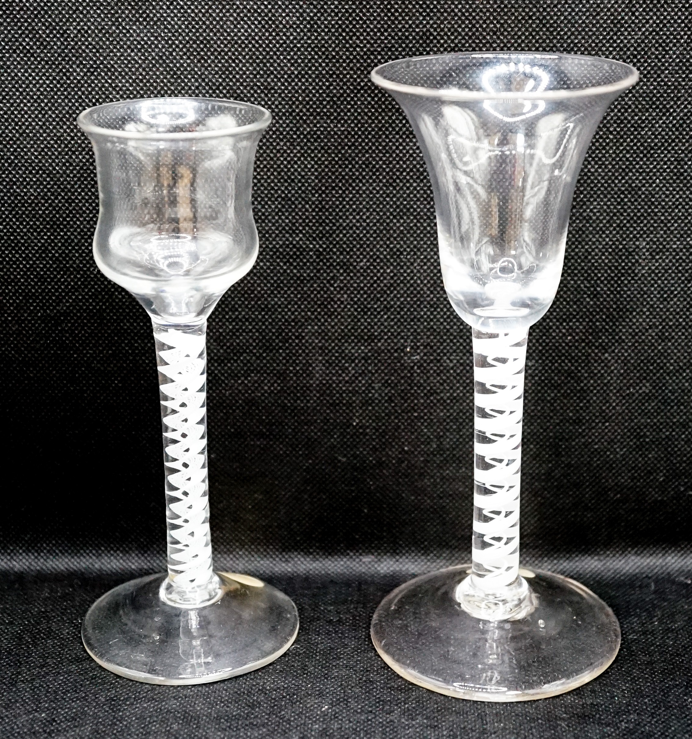 Two George III opaque twist stem cordial glasses, c.1760, each with a double series opaque twist stem, one with a bell shaped bowl the other with an ogee shaped bowl, 15 & 16cm